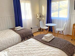 奥尔穆埃Novaqua Bed & Breakfast的一间卧室设有两张床、一张桌子和一个窗口