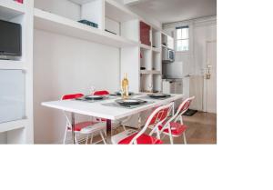 勒瓦卢瓦-佩雷La petite maison parisienne的厨房配有白色的桌子和红色的椅子