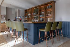柯罗格伦都柏林机场卡尔顿酒店的一间酒吧,在一间房间里设有绿色的酒吧凳子