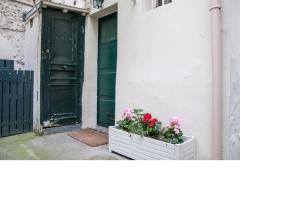 勒瓦卢瓦-佩雷La petite maison parisienne的门旁有花的白色板条