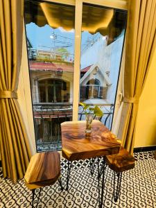胡志明市Anam Homestay的一张桌子和一张长凳,位于大窗户前