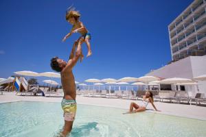 阿雷纳尔登卡斯特尔Palladium Hotel Menorca的男人和孩子跳进游泳池