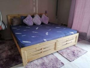 达喀尔Bienvenue CHEZ VOUS的一张带蓝色床单和枕头的木床