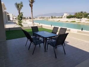 塞拉莱Hawana Salalah Villa Lake View的水边天井上的桌椅