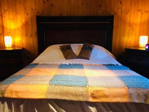 圣何塞德迈波Campito Refugio的一张带五颜六色被子的床和两张台灯