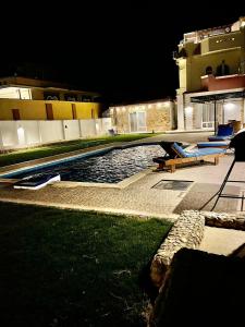 赫尔格达Villa Sky的一座游泳池,晚上在大楼旁边摆放着蓝色的椅子