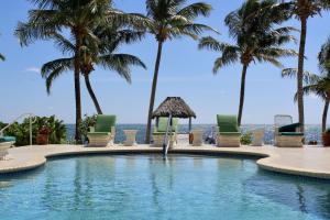 圣佩德罗Tara Del Sol Resort的一座棕榈树和椅子的游泳池