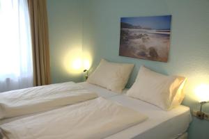莱茵河畔路德维希港Hotel Yel的一间卧室配有两张带白色床单和枕头的床。