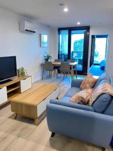 堪培拉Central Canberra City apartment with study and full amenities including parking的客厅配有蓝色的沙发和电视