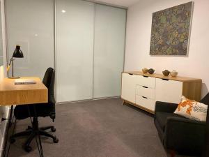 堪培拉Central Canberra City apartment with study and full amenities including parking的办公室配有书桌、椅子和书桌