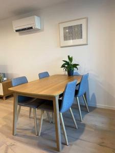 堪培拉Central Canberra City apartment with study and full amenities including parking的一张带椅子的木桌和一盆盆植物