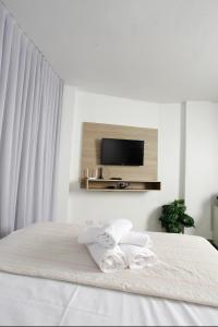 戈亚尼亚Apartamento 1009的白色卧室配有带2条毛巾的床