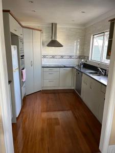 旺阿雷Tamaterau Seaview House in Whangarei的厨房铺有木地板,配有白色橱柜。