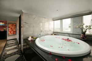 河内HOTEL du LAC Hanoi的浴室设有大浴缸,内配红色鲜花