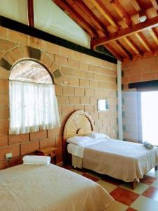 圣胡安德里奥Casa Ikal en San Juan del Rio con Alberca y Temazcal.的一间卧室设有两张床和砖墙
