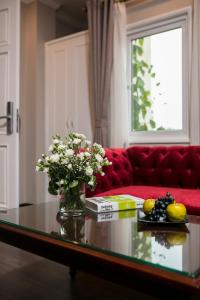 河内Flora Centre Hotel & Spa的客厅配有红色的沙发和带鲜花的玻璃桌