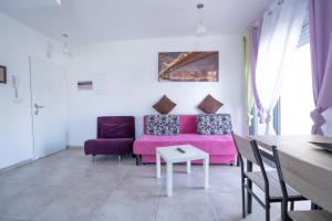 埃拉特Yam Suf By Sun and View的客厅配有粉红色的沙发和椅子