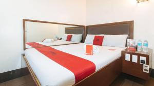 马尼拉RedDoorz @ Riches Holiday Hotel Avenida的一间卧室配有两张红色和白色床单