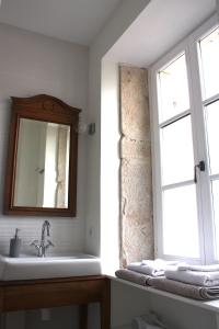 博讷Le 14 Faubourg的一间带水槽和镜子的浴室以及窗户。