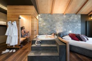 利维尼奥拉克萨林温泉山区度假酒店的一间带浴缸和床的卧室以及镜子中的男人