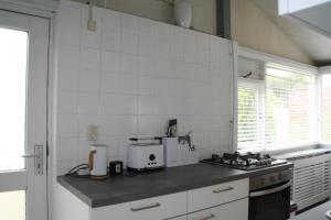 SchoorldamRekerlanden 90的厨房设有白色的瓷砖墙壁和台面
