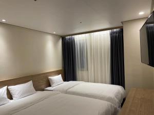 首尔The garden hotel的一间卧室设有两张床和窗户。