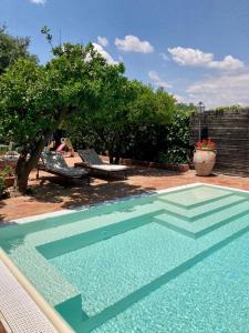 卡尔塔尼塞塔La zagara e l'arancio的庭院内的游泳池,配有桌子和长凳