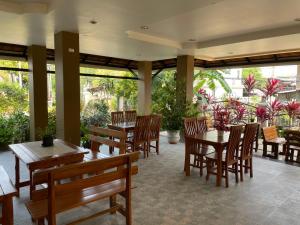 清迈Laph Kham House的餐厅设有木桌和椅子,种有植物