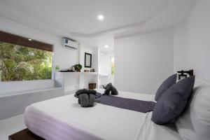 Phra Ae beachEl Matcha Lanta Resort的白色卧室配有一张带蓝色枕头的大床