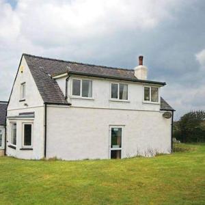 LlanrhyddladThe Lobster Pot Cottage Church Bay的绿色田野顶上的白色房子