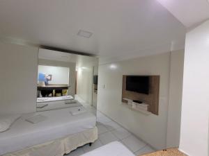 若昂佩索阿Hotel Victory Business Flat Beira Mar Tambaú的客房设有两张床、一台电视和镜子