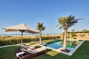 阿布扎比Club Privé By Rixos Saadiyat的一个带椅子和遮阳伞的游泳池,并种植了棕榈树