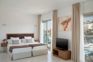 克里斯托港Porto Drach Aparthotel & Suites的一间卧室配有一张床和一台平面电视
