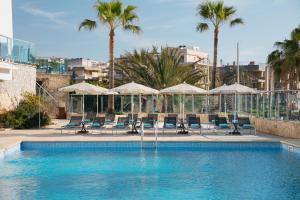 克里斯托港Porto Drach Aparthotel & Suites的一个带椅子和遮阳伞的游泳池以及棕榈树