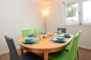 InnellanPedals and Paddles的一间带木桌和绿色椅子的用餐室