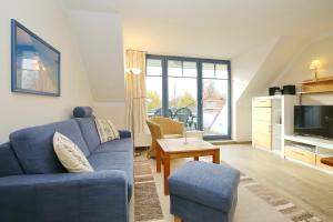 博尔滕哈根Papillon Wohnung 01-6的客厅配有蓝色的沙发和电视