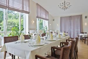 瑞斯布特尔My Suite Leesch - Hotel & Restaurant nahe Büsum - Hunde herzlich willkommen的一间设有白色桌椅和窗户的用餐室