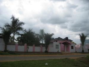 MbaleR&R Gardens Hotel的棕榈树掩护下的白色房子