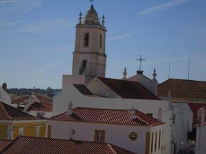 阿尔坎塔里利亚Casa Azul em Alcantarilha - Algarve的一座建筑,有一个钟楼,有红色的屋顶