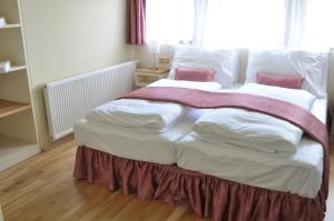 克拉斯纳利帕利巴膳食公寓的一张配有白色床单和粉红色枕头的大床