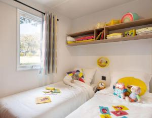维琪奥港Camping La Baie des Voiles的一间卧室配有两张床和玩具