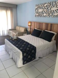 布希奥斯Hotel Búzios Resort com Entretenimento的一间卧室配有一张大床和一张沙发