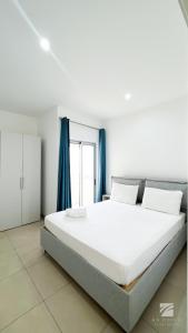 萨尔雷Ka Djula的卧室配有一张带蓝色窗帘的大型白色床