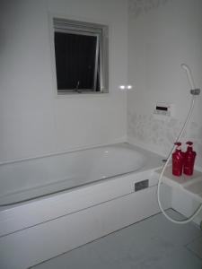 大阪大阪库马楼旅馆的白色的浴室设有浴缸和窗户