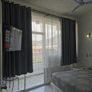 锡瓦塔塔内霍1 BR APT with AC , TV , wi-fi near DT and beach的一间卧室配有黑色窗帘和大窗户