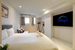 台北慕居行旅的卧室配有一张白色大床,墙上配有电视