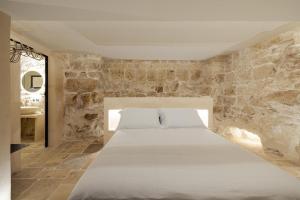 奥斯图尼Suite Le Grotte的卧室配有石墙内的白色床