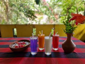 希克杜沃Nimal`s Homestay的一张桌子,上面有四种不同的颜色饮料和一碗食物