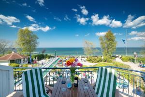 瓦尔内明德威尔赫姆索赫酒店的阳台配有桌椅,享有海滩美景
