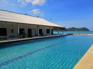 通奈潘海滩Thong Nai Pan Beach Resort的一座游泳池,位于一座建筑的旁边,以大海为背景